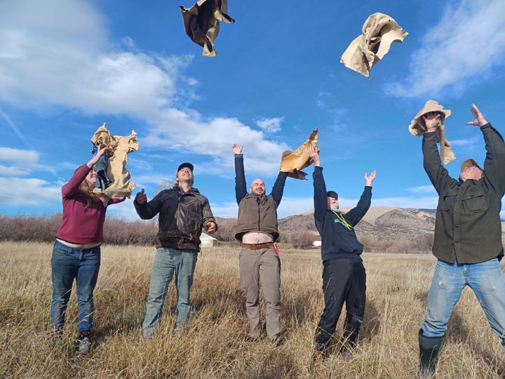 Students toss braintan hides in the air.