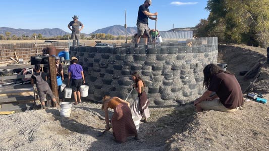 Building a circular toolshed from old tires packed with earth.